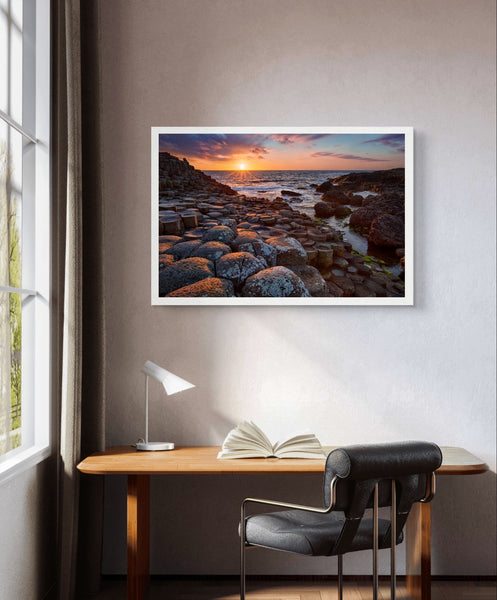 Framed art print of a mesmerizing sunset at Giant's Causeway, featuring iconic basalt columns under a sky painted with warm hues. Captures nature's beauty and tranquility, adding a sophisticated touch to any home or office decor. Ideal for art enthusiasts.