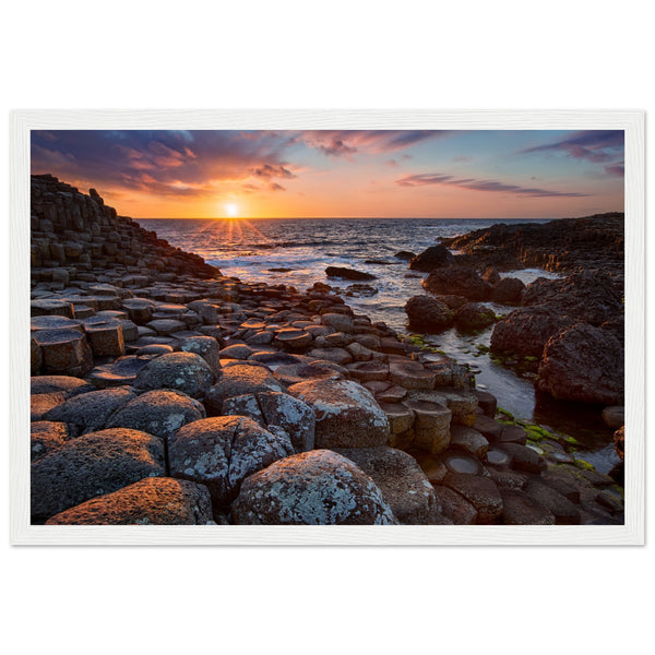 Framed art print of a mesmerizing sunset at Giant's Causeway, featuring iconic basalt columns under a sky painted with warm hues. Captures nature's beauty and tranquility, adding a sophisticated touch to any home or office decor. Ideal for art enthusiasts.
