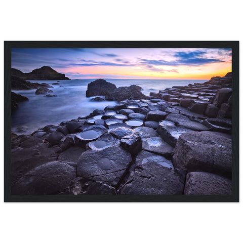 Framed art print of a breathtaking sunset at Giant's Causeway. Features iconic basalt columns against a warm, colorful sky. Perfect for adding sophistication and natural beauty to any home or office decor. Ideal for nature and art enthusiasts.