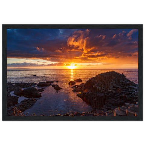 Framed art print of a mesmerizing sunset at Giant's Causeway, showcasing iconic basalt columns against a sky painted with warm hues. The scene captures nature's beauty and tranquility, adding a sophisticated touch to home or office decor. Perfect for any art lover.